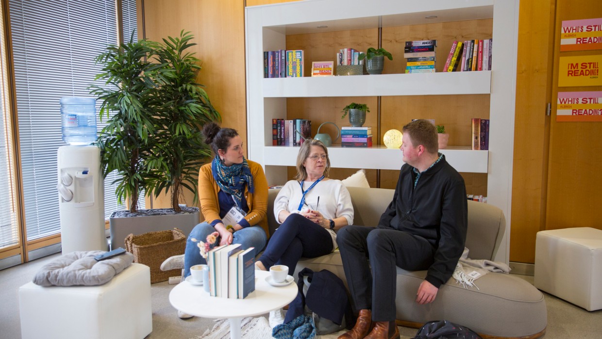 Bloggerlounge mit 3 Personen auf einem Sofa vor einem Bücherregal während der Leipziger Buchmesse 2024