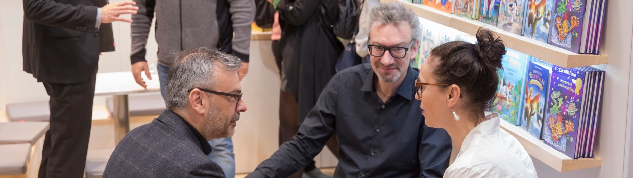 Personen im Gespräch an einem Messestand während der Leipziger Buchmesse 2024