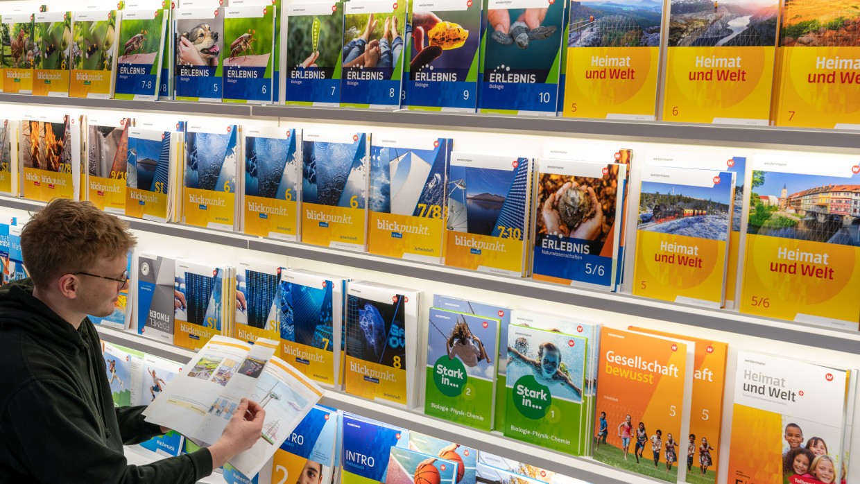 Lesender Besucher an einem Messestand mit großem Bücherregal auf der Leipziger Buchmesse 2024