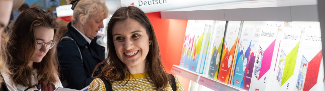 Lesende Besucherin an einem Messestand mit großem Bücherregal auf der Leipziger Buchmesse 2024