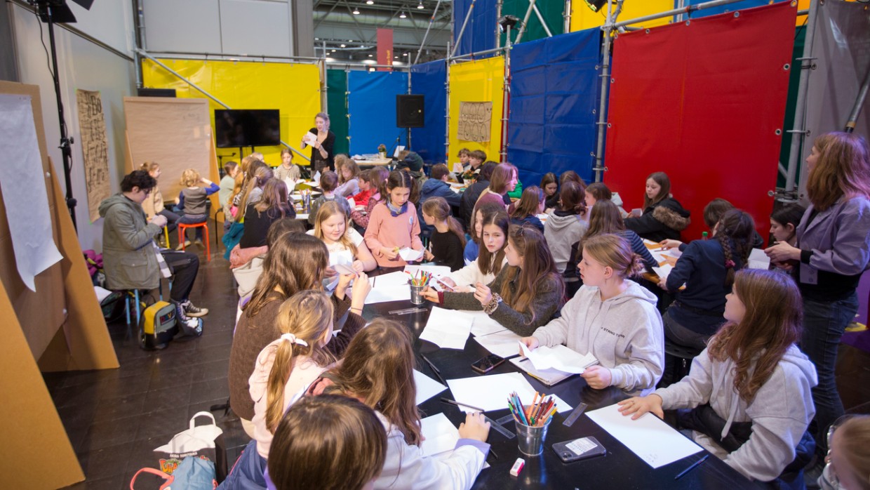 Kinder malen an großen Tischen im UVERSE auf der Leipziger Buchmesse 2024